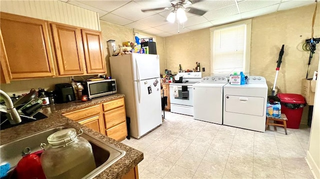 kitchen with sink, washing machine and clothes dryer, a drop ceiling, white appliances, and ceiling fan