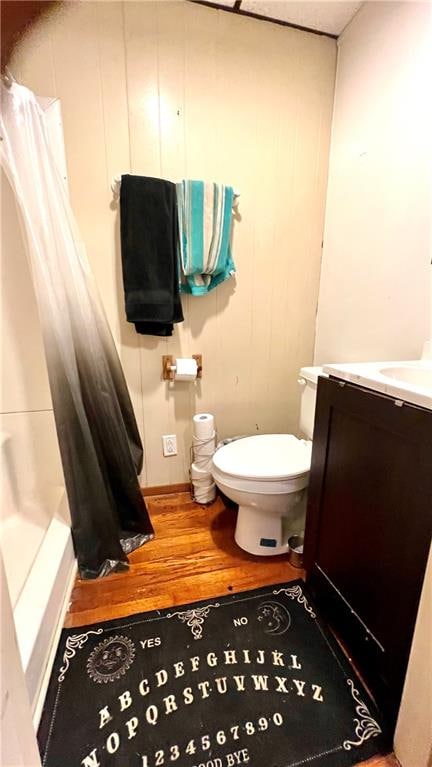 full bathroom featuring wood-type flooring, vanity, shower / tub combo, and toilet