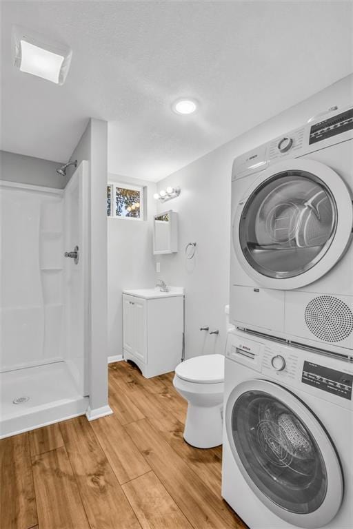 interior space with walk in shower, stacked washer and clothes dryer, vanity, and wood-type flooring