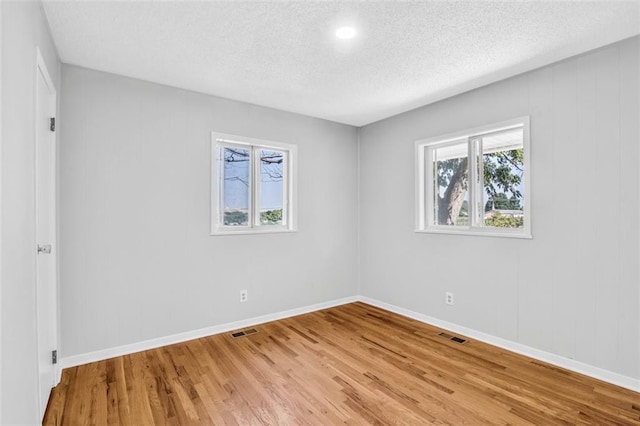 spare room with a textured ceiling and hardwood / wood-style flooring