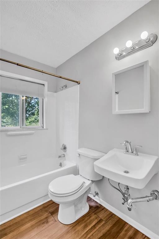 full bathroom featuring toilet, sink, a textured ceiling, shower / bathtub combination, and hardwood / wood-style floors