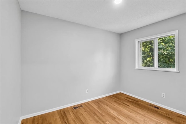 empty room with hardwood / wood-style flooring and a textured ceiling