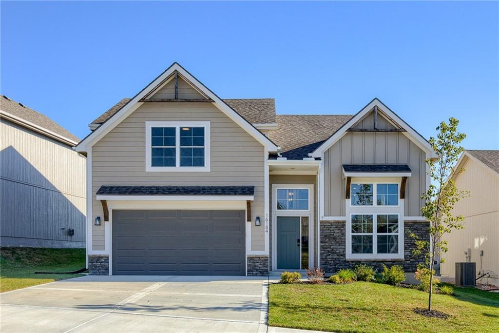 craftsman-style house featuring cooling unit, a garage, and a front lawn