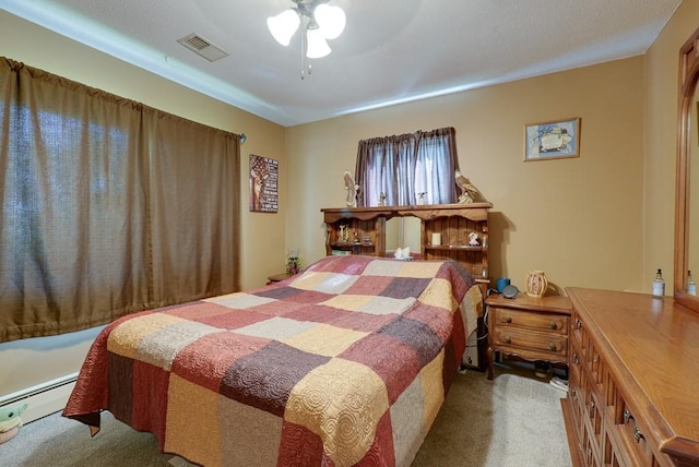 carpeted bedroom featuring a baseboard heating unit, visible vents, and a ceiling fan