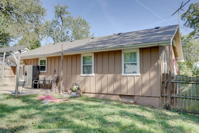 rear view of house with a yard, fence, board and batten siding, and a patio