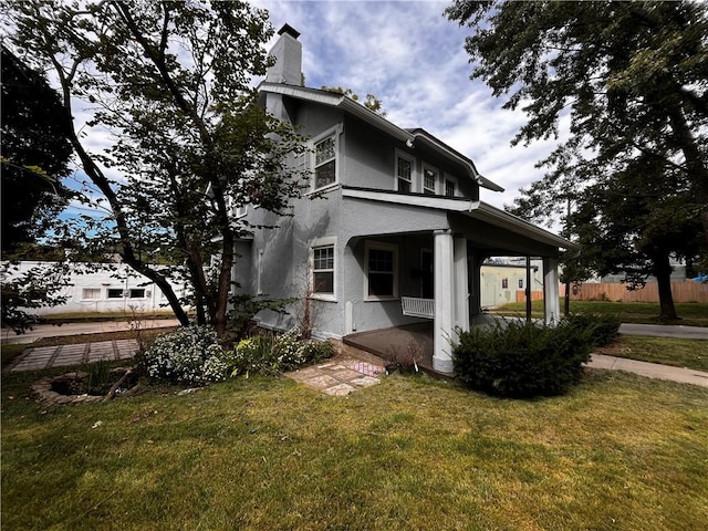 view of side of property with a porch and a lawn