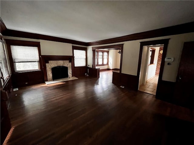 unfurnished living room with a healthy amount of sunlight, crown molding, dark hardwood / wood-style flooring, and a premium fireplace