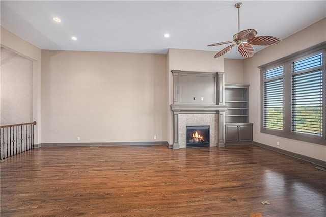 unfurnished living room featuring ceiling fan, dark hardwood / wood-style floors, and a tiled fireplace