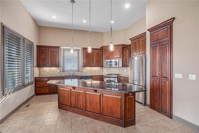 kitchen featuring a kitchen island, stainless steel appliances, sink, pendant lighting, and dark stone counters