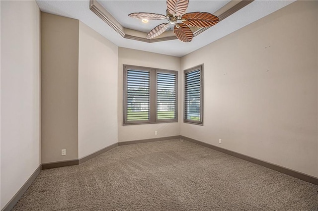 empty room featuring carpet floors, a raised ceiling, and ceiling fan