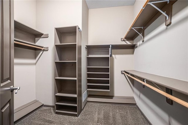 walk in closet featuring dark colored carpet