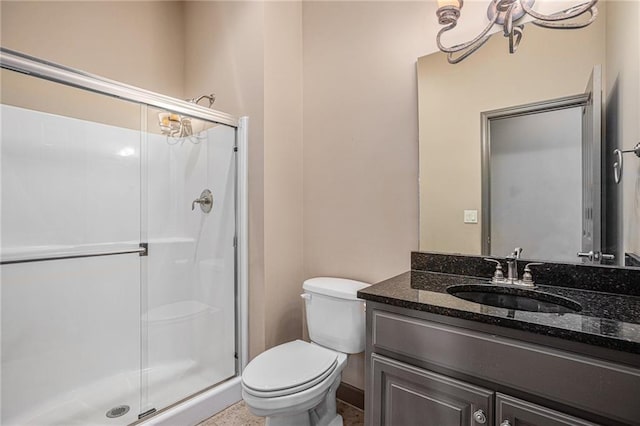 bathroom featuring vanity, a shower with door, and toilet