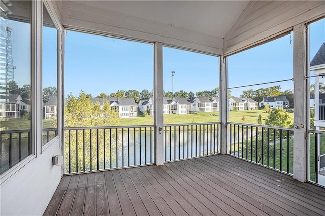 unfurnished sunroom with lofted ceiling, plenty of natural light, and a water view