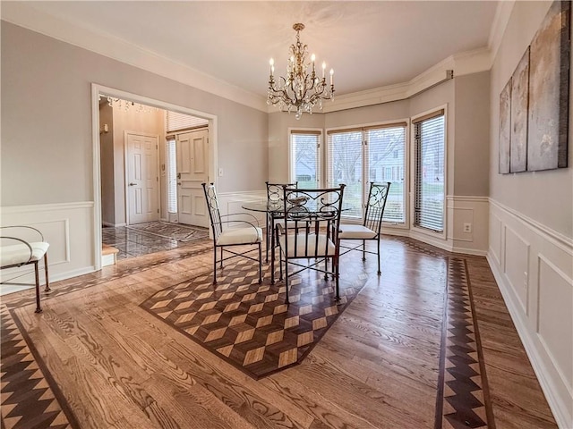 dining space featuring wood-type flooring, crown molding, and a chandelier