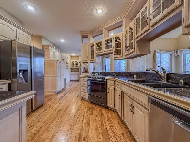 kitchen with a textured ceiling, stainless steel appliances, sink, light brown cabinets, and light hardwood / wood-style flooring