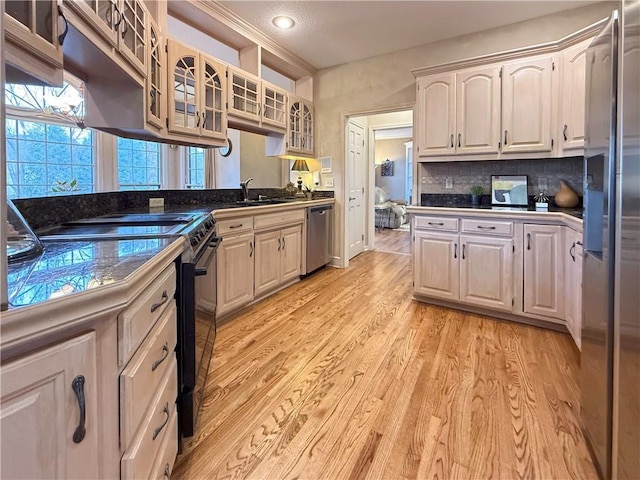 kitchen featuring sink, dishwasher, light hardwood / wood-style flooring, black / electric stove, and decorative backsplash