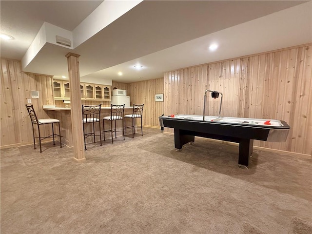 recreation room with bar area, wooden walls, and light carpet