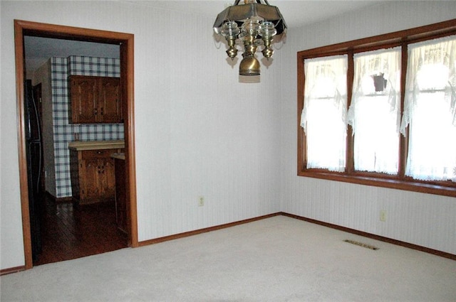 unfurnished room featuring a chandelier and carpet flooring