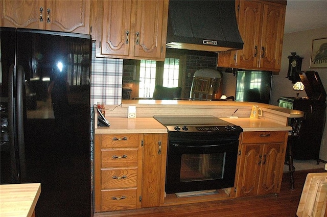 kitchen with decorative backsplash, dark hardwood / wood-style floors, wall chimney exhaust hood, and black appliances