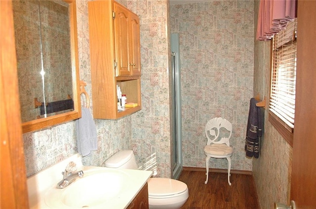 bathroom featuring hardwood / wood-style flooring, vanity, toilet, and a shower with shower door