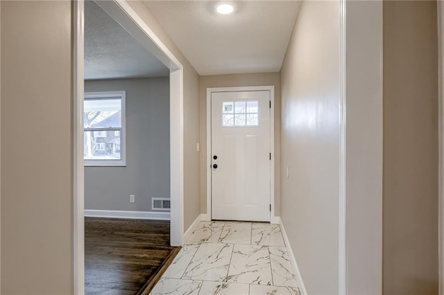 entryway with a textured ceiling, light hardwood / wood-style flooring, and a healthy amount of sunlight