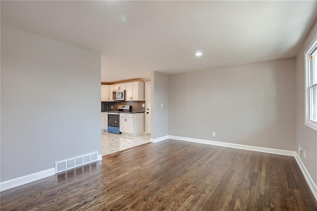 unfurnished living room with dark hardwood / wood-style flooring and a textured ceiling