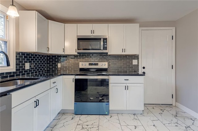 kitchen featuring backsplash, white cabinetry, stainless steel appliances, and decorative light fixtures