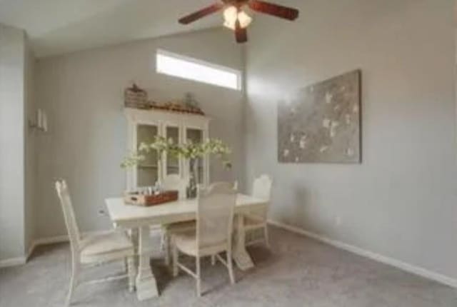 carpeted dining area with ceiling fan and lofted ceiling