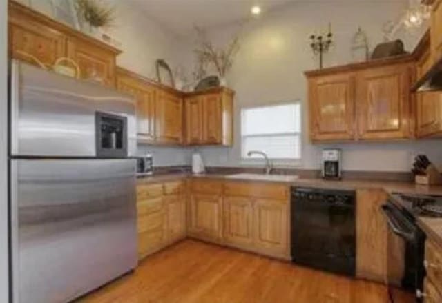 kitchen with black appliances, light hardwood / wood-style floors, and sink