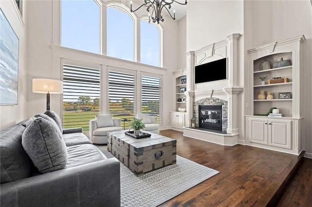 living room with a chandelier, built in features, a towering ceiling, and dark wood-type flooring