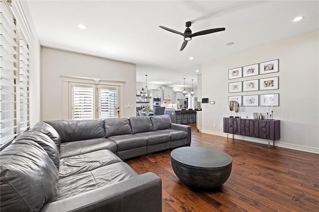 living room featuring ceiling fan with notable chandelier and dark hardwood / wood-style flooring