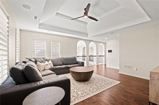 living room featuring a tray ceiling, ceiling fan, and dark hardwood / wood-style floors