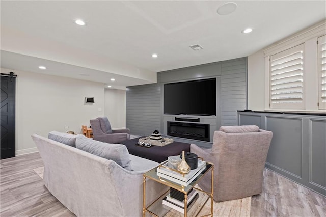 living room with a barn door and light wood-type flooring