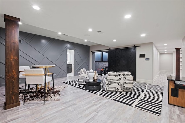 living room featuring a barn door, light hardwood / wood-style flooring, and ornate columns