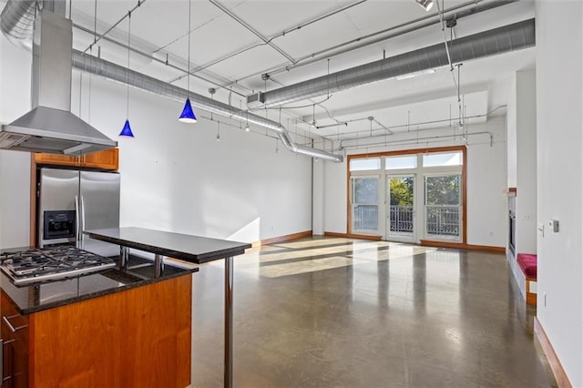 interior space featuring dark stone countertops, decorative light fixtures, stainless steel appliances, and range hood