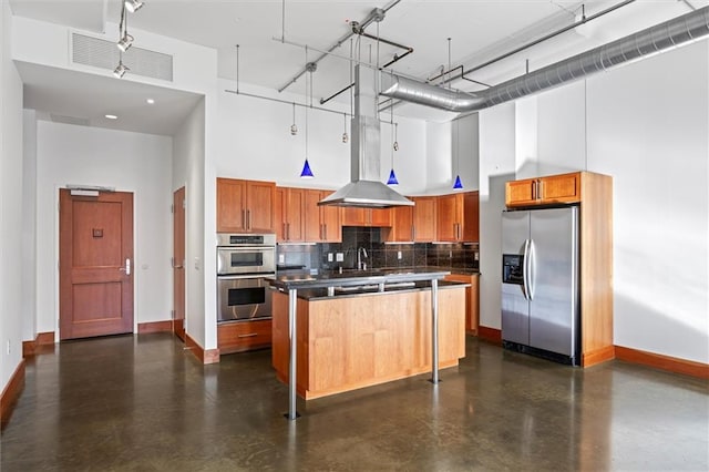 kitchen featuring a high ceiling, decorative backsplash, island exhaust hood, a kitchen island, and stainless steel appliances