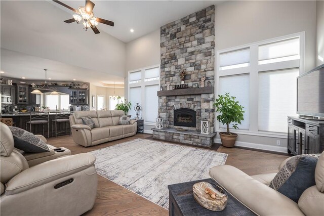 living room featuring a high ceiling, ceiling fan, a fireplace, and dark hardwood / wood-style flooring