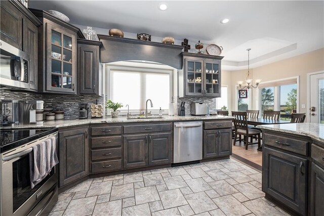 kitchen featuring appliances with stainless steel finishes, decorative backsplash, light stone countertops, pendant lighting, and sink