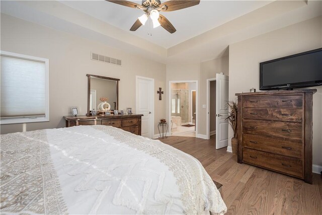 bedroom featuring light wood-type flooring, connected bathroom, and ceiling fan