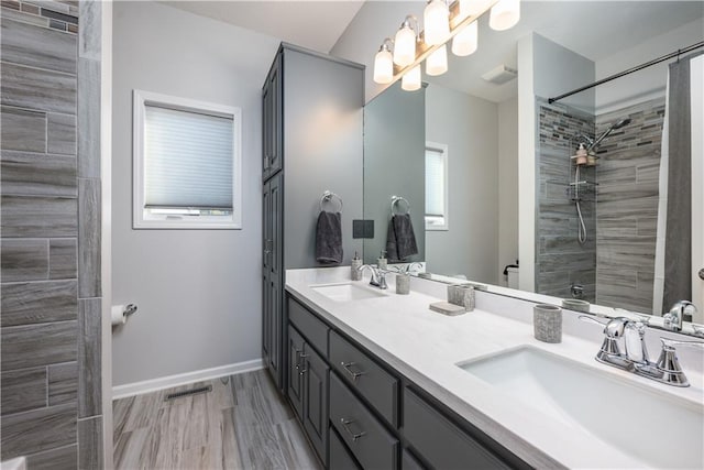 bathroom with wood-type flooring, vanity, and a tile shower