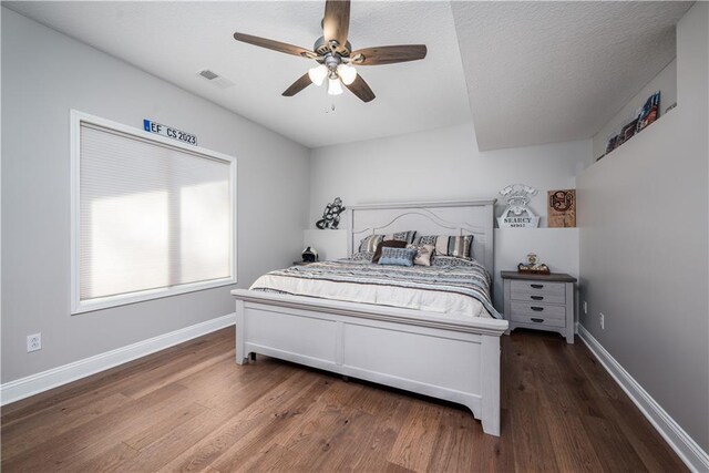 bedroom featuring a textured ceiling, dark wood-type flooring, and ceiling fan