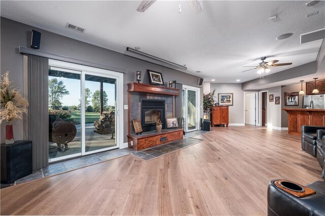 living room featuring ceiling fan, a textured ceiling, and light hardwood / wood-style floors