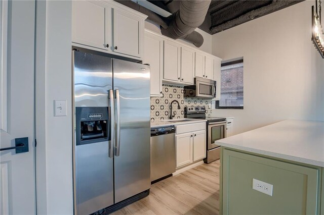 kitchen featuring light hardwood / wood-style flooring, sink, white cabinetry, appliances with stainless steel finishes, and tasteful backsplash