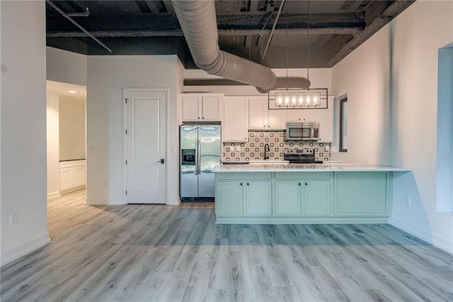 kitchen with appliances with stainless steel finishes, light hardwood / wood-style flooring, white cabinets, and decorative light fixtures