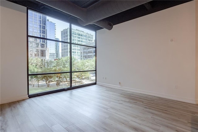 unfurnished room featuring expansive windows and wood-type flooring