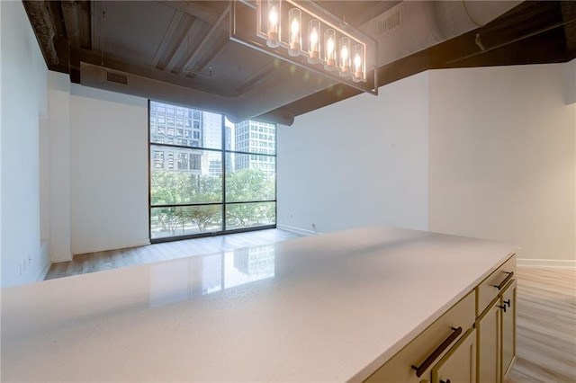 kitchen with light hardwood / wood-style floors, a wall of windows, and cream cabinetry