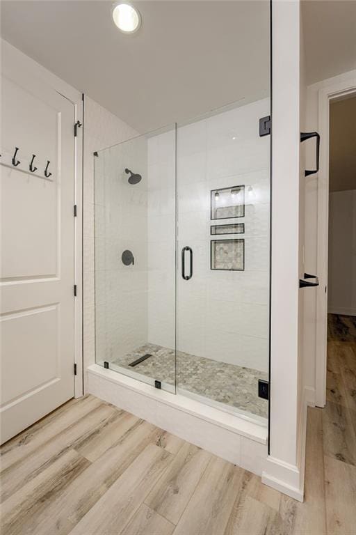 bathroom with a shower with door and wood-type flooring