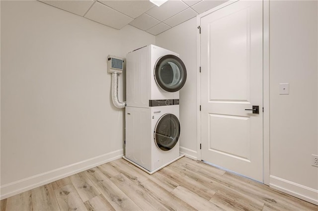 clothes washing area featuring light hardwood / wood-style floors and stacked washing maching and dryer