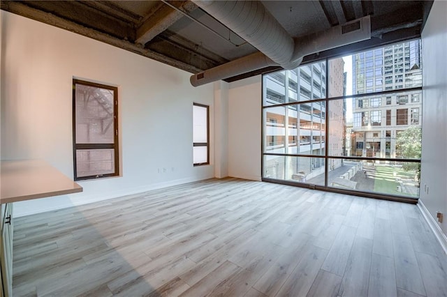 unfurnished living room featuring floor to ceiling windows and light wood-type flooring