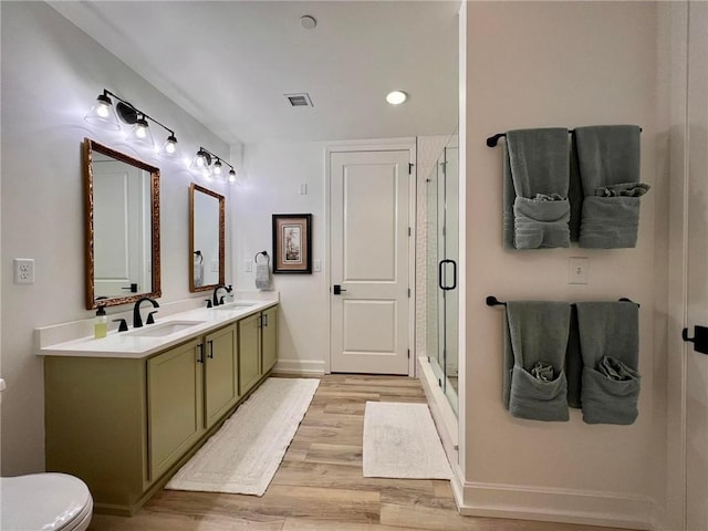 bathroom with toilet, vanity, a shower with door, and hardwood / wood-style floors